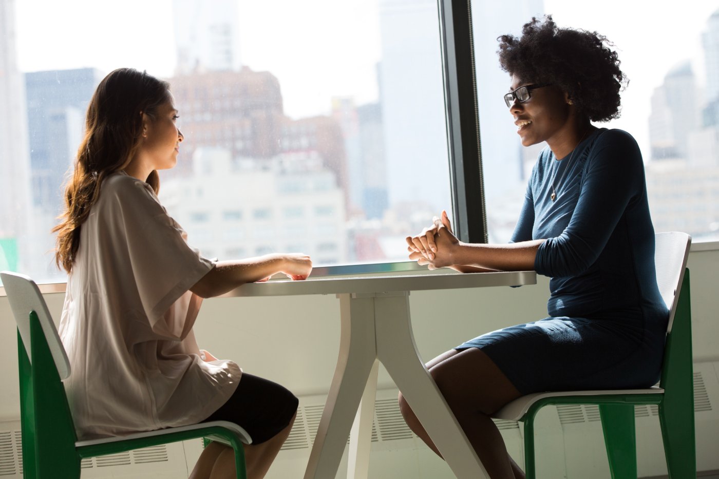 Dos mujeres jóvenes charlando en una mesa redonda