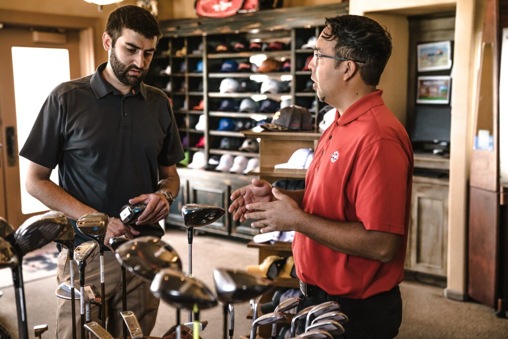 Dependiente de una tienda de golf realiza una encuesta a un cliente